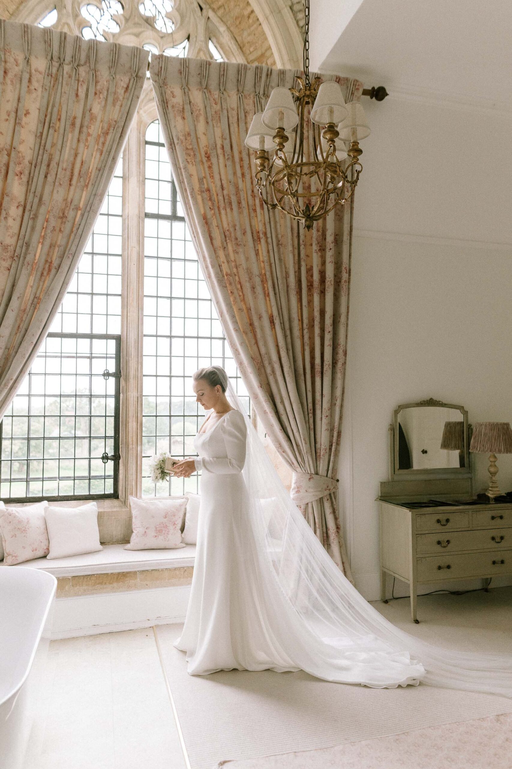 bridal portrait with veil in window of bridal suite at Butley Priory