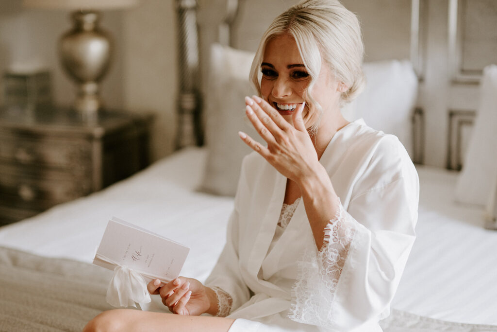 bride opening letter from her groom on her wedding morning at Woodhall manor