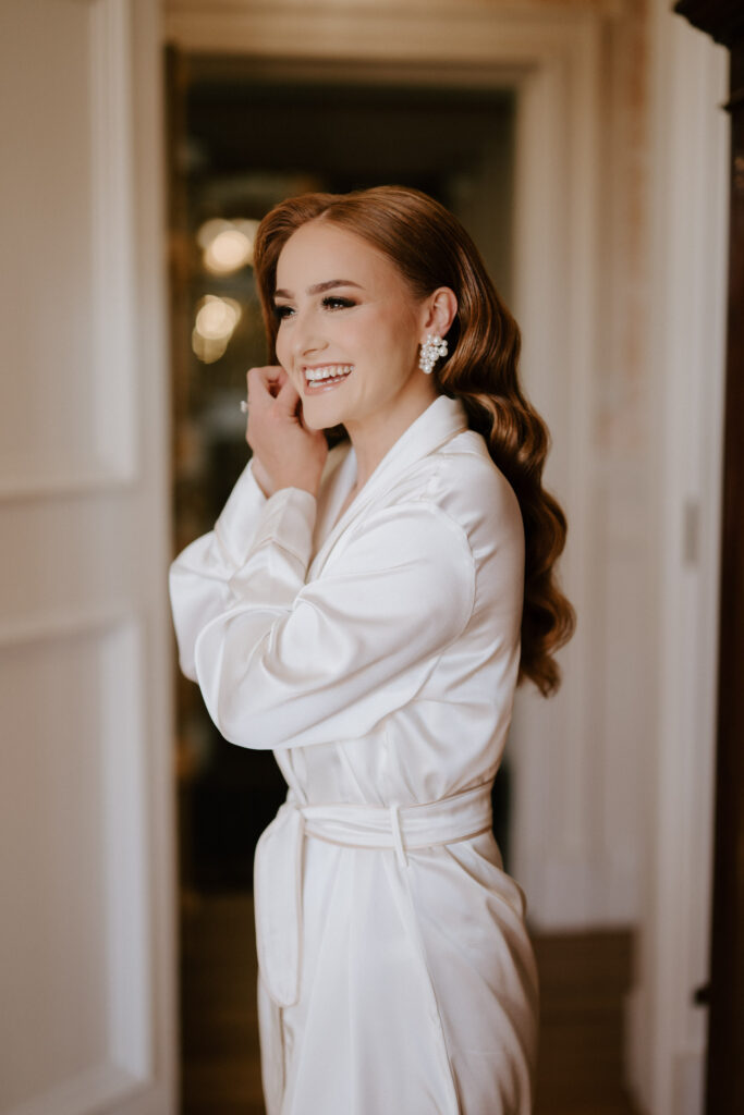 bride putting on pearl earrings on wedding morning