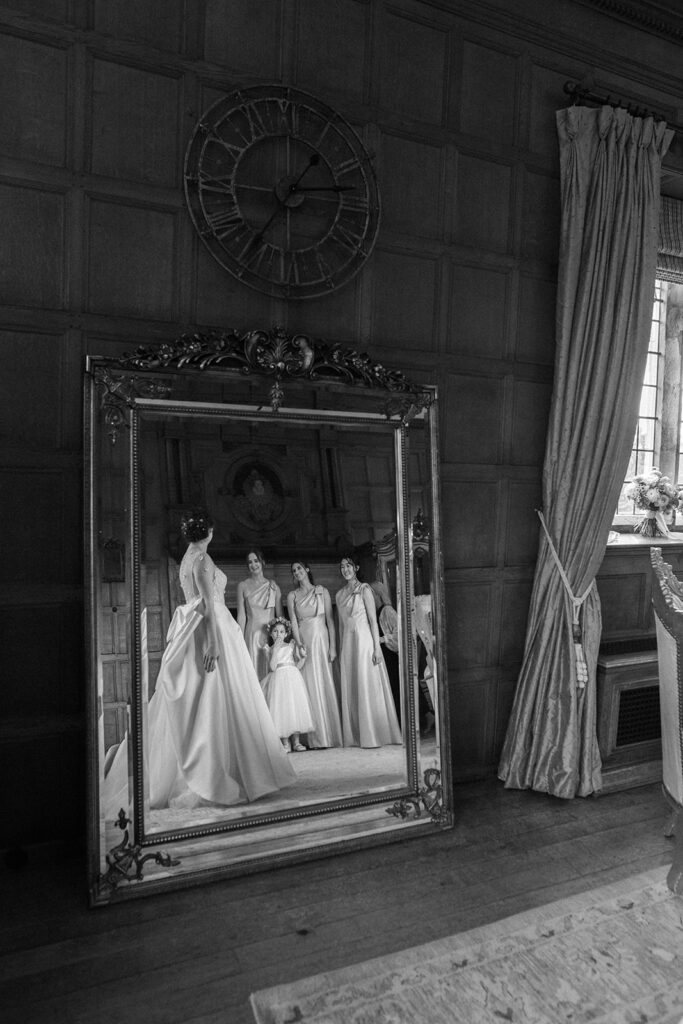 reflection of bride and bridesmaids in mirror in bridal suite at hengrave hall