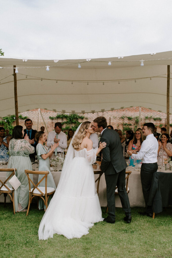 bride and groom kissing at marquee reception at the walled garden in wilderness reserve