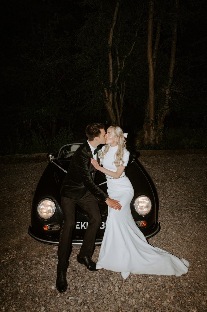 couple at night sitting on vintage wedding car at West Green house gardens