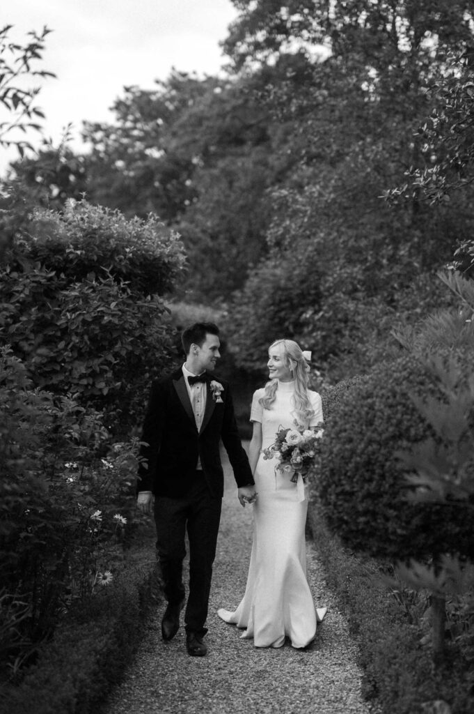 bride and groom walking through gardens at West Green house gardens