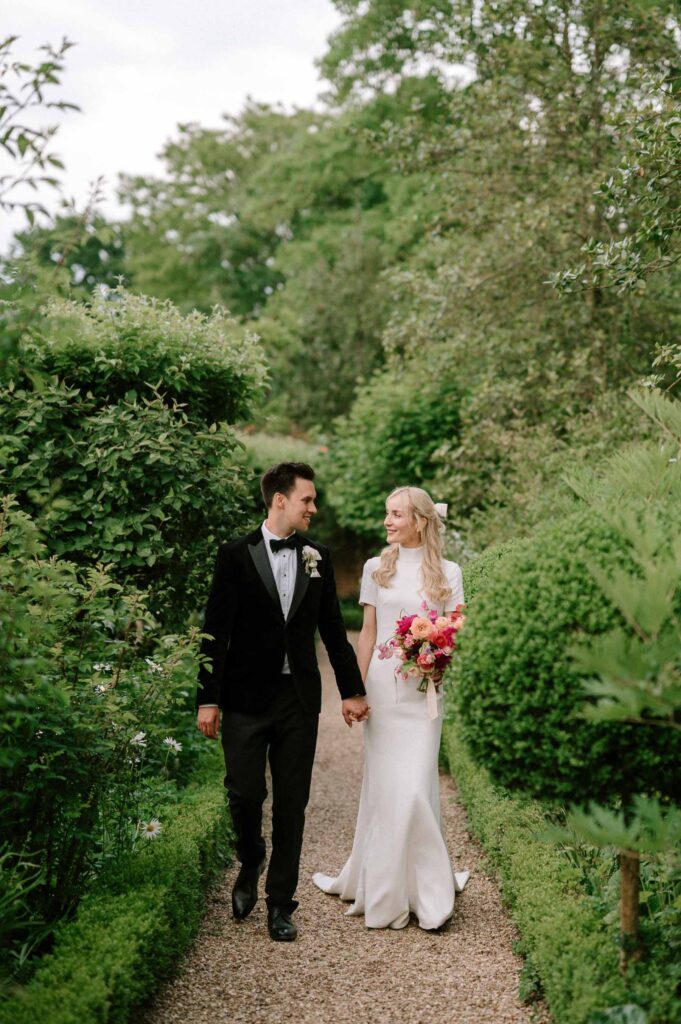 bride and groom walking through gardens at West Green house gardens