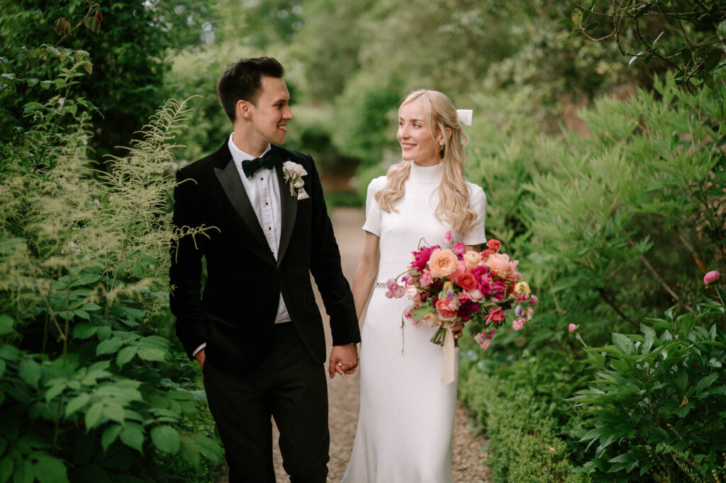 bride and groom walking through gardens at West Green house gardens