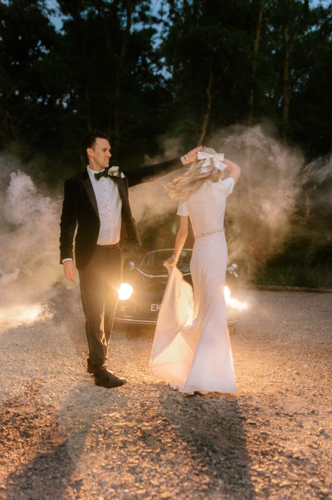 bride and groom dancing at night in front of vintage wedding car