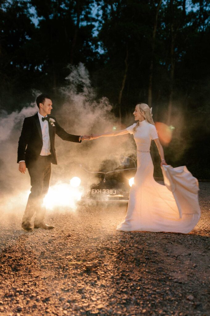 bride and groom dancing at night in front of vintage wedding car