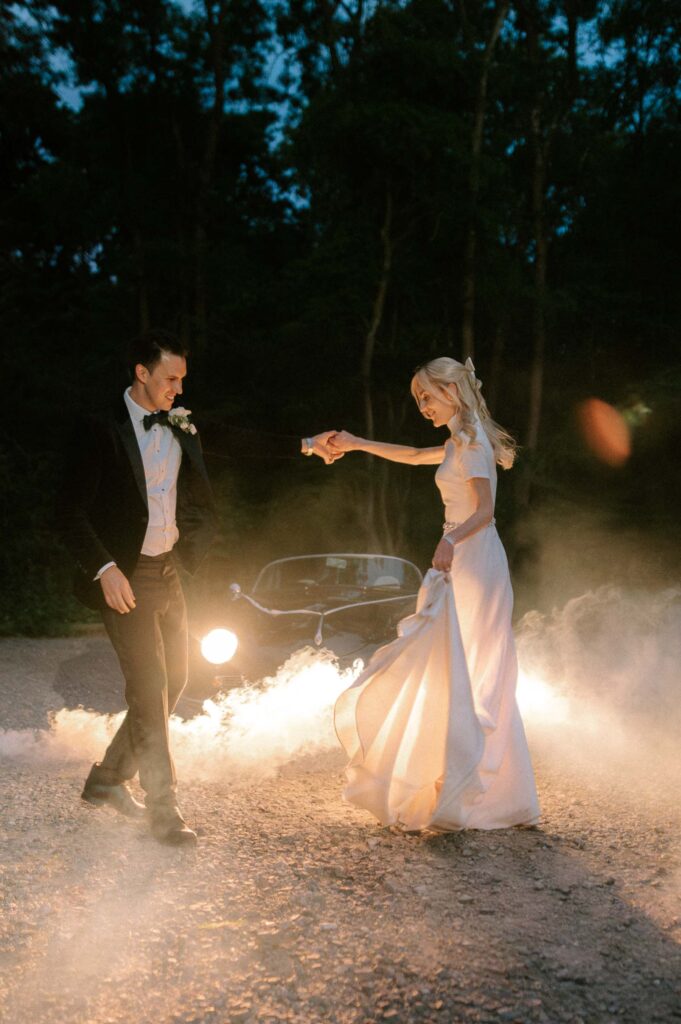 bride and groom dancing at night in front of vintage wedding car