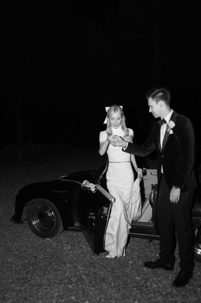 groom helping bride out of the wedding car