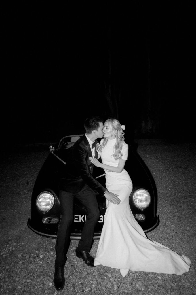 bride and groom kissing on vintage wedding car