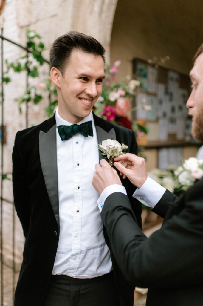 best man putting on grooms buttonhole