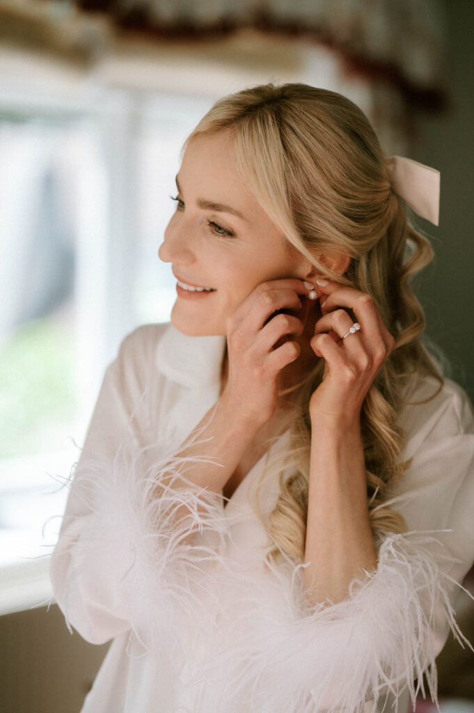 bride putting her earrings on on wedding morning
