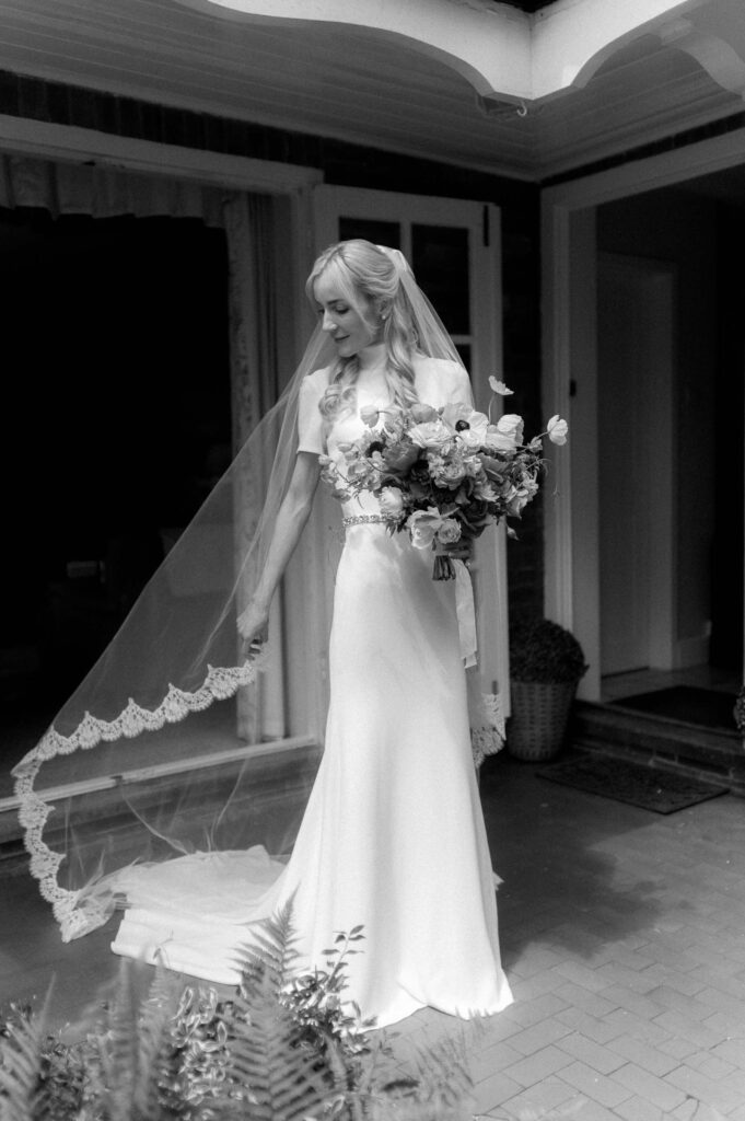 bride playing with lace veil in garden on wedding morning