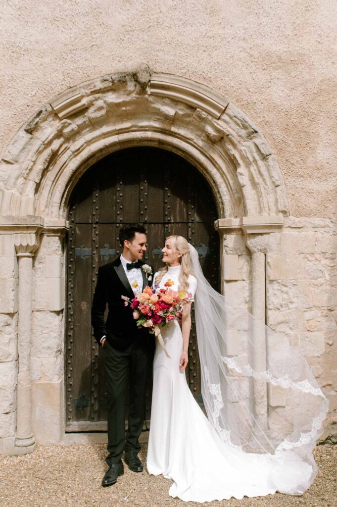 bride and groom smiling outside church in Hampshire after wedding