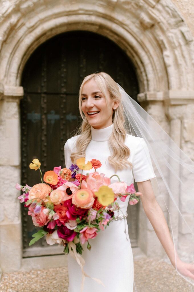 candid moment of bride smiling whilst holding her bouquet