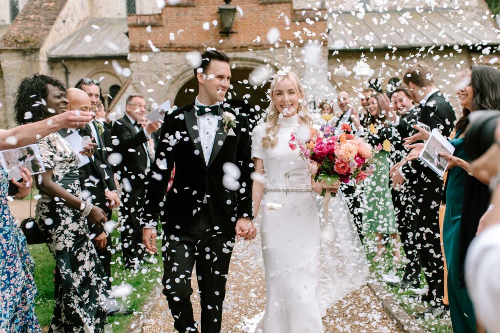 bride and groom walking out of church with guests throwing white confetti