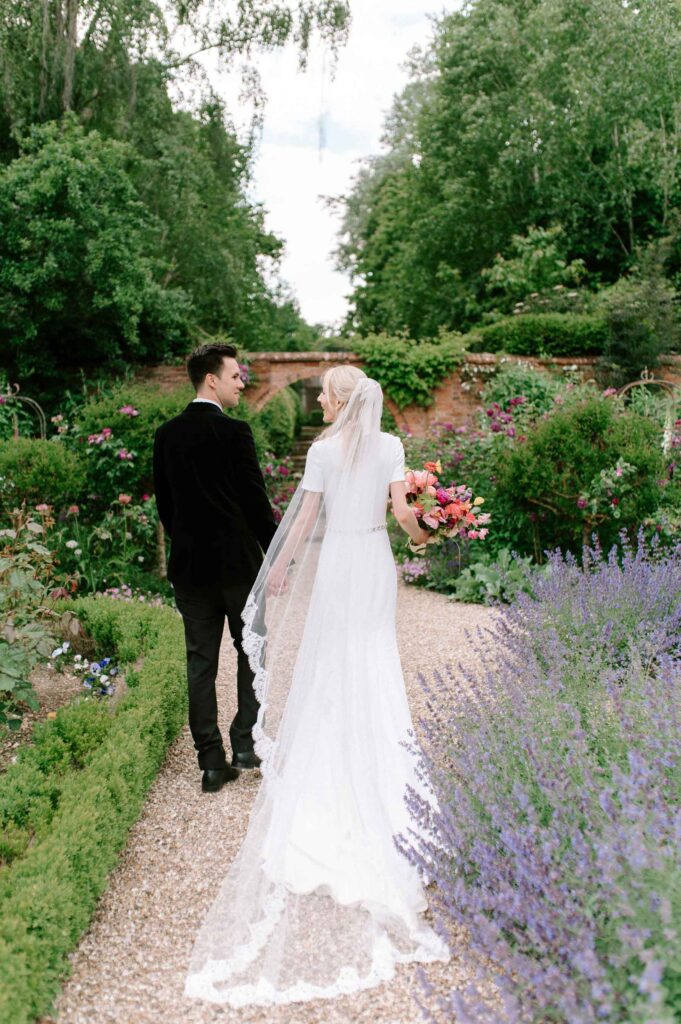 bride and groom walking away in gardens of West Green house gardens wedding venue
