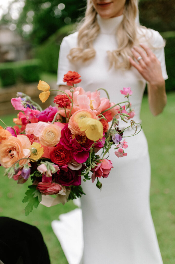 bride holding her colourful summer bouquet with yellow, pinks, reds and oranges