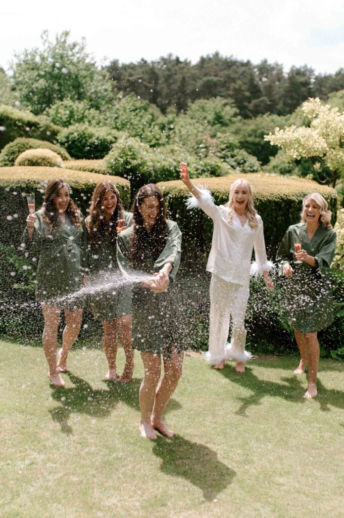 bridesmaids spraying champagne in the garden on wedding morning