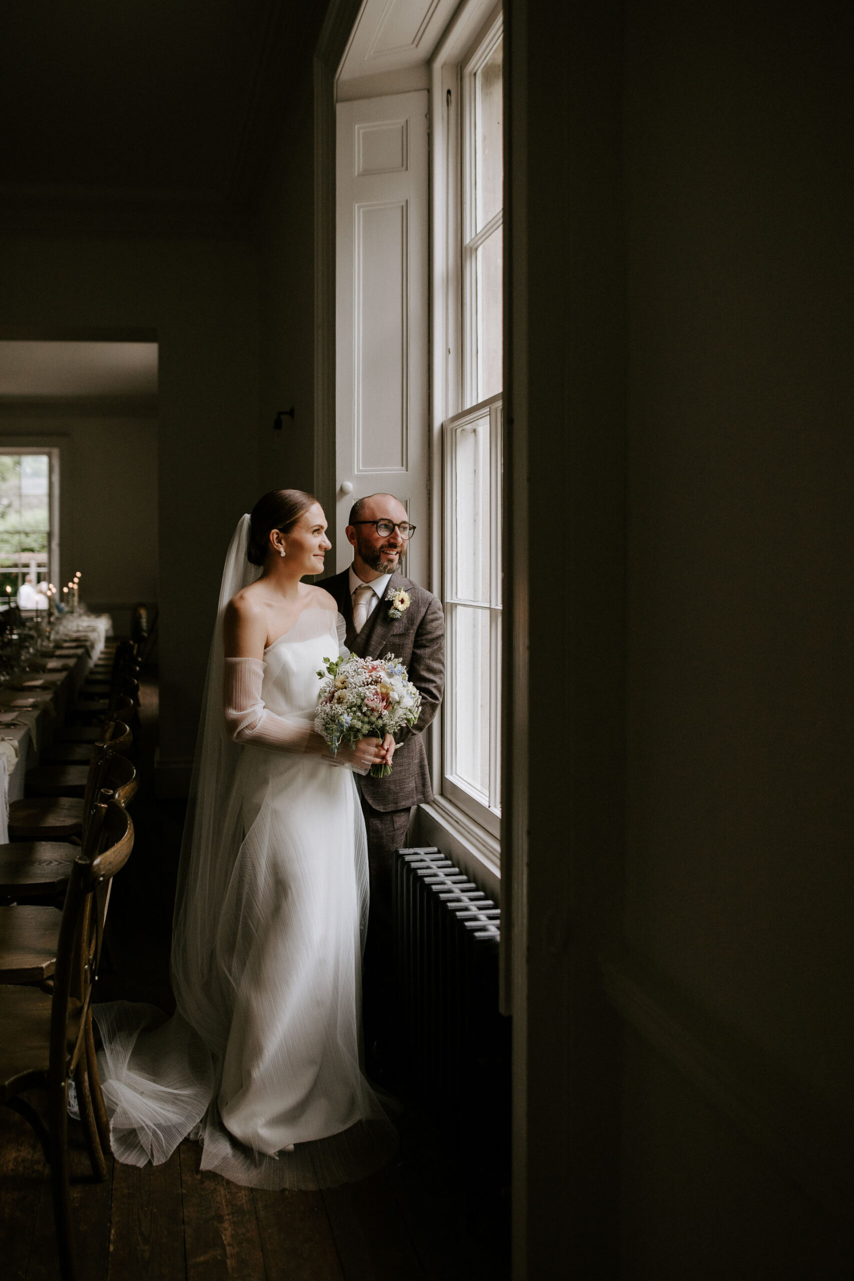 editorial bride and groom in aswarby rectory looking out of window in wedding breakfast reception room