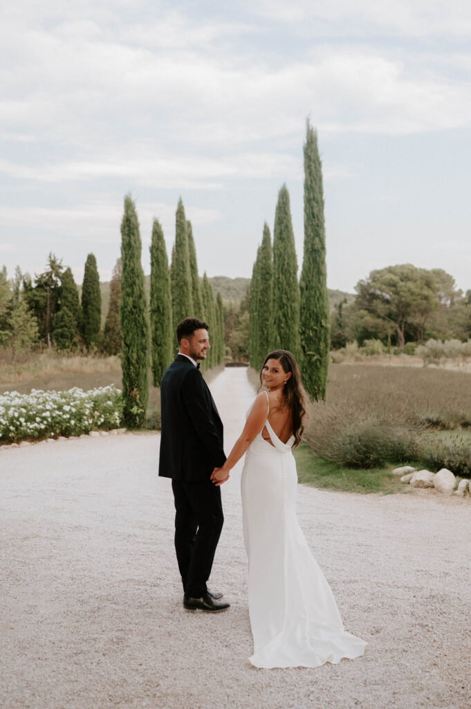 couple walking down tree lined road at le mas des costes in provence