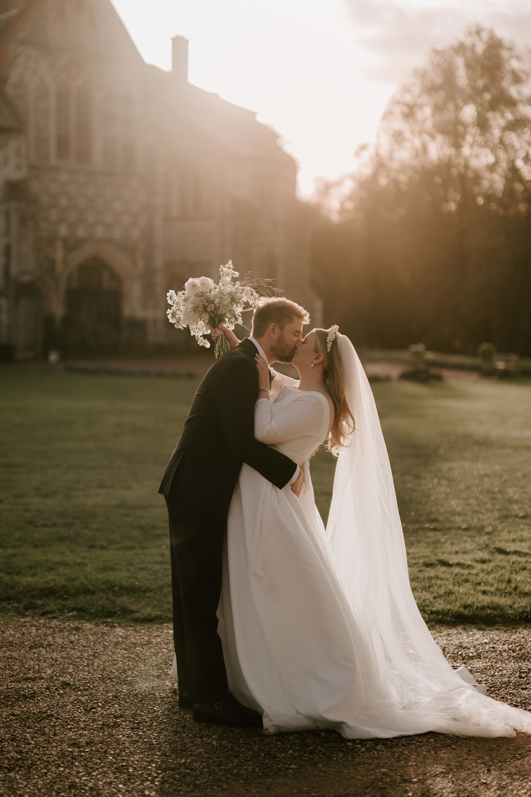 bride and groom portrait at sunset with butley priory in the background
