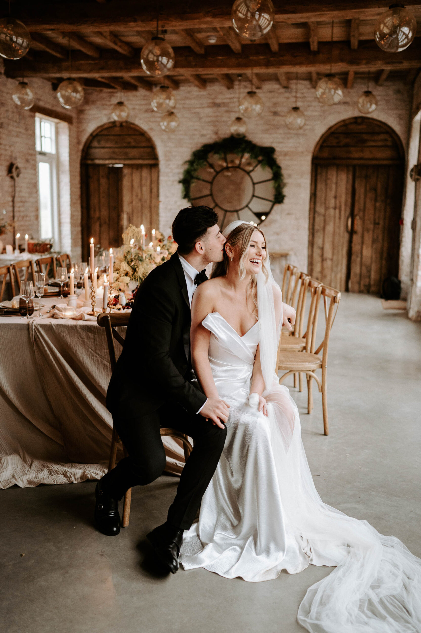 bride and groom sat at wedding breakfast table laughing