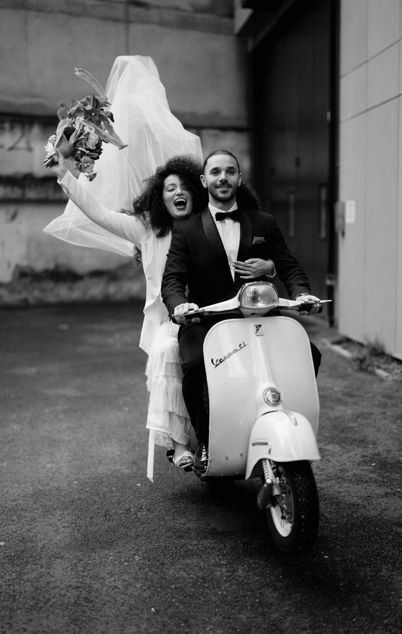 bride and groom riding vespa down streets of london