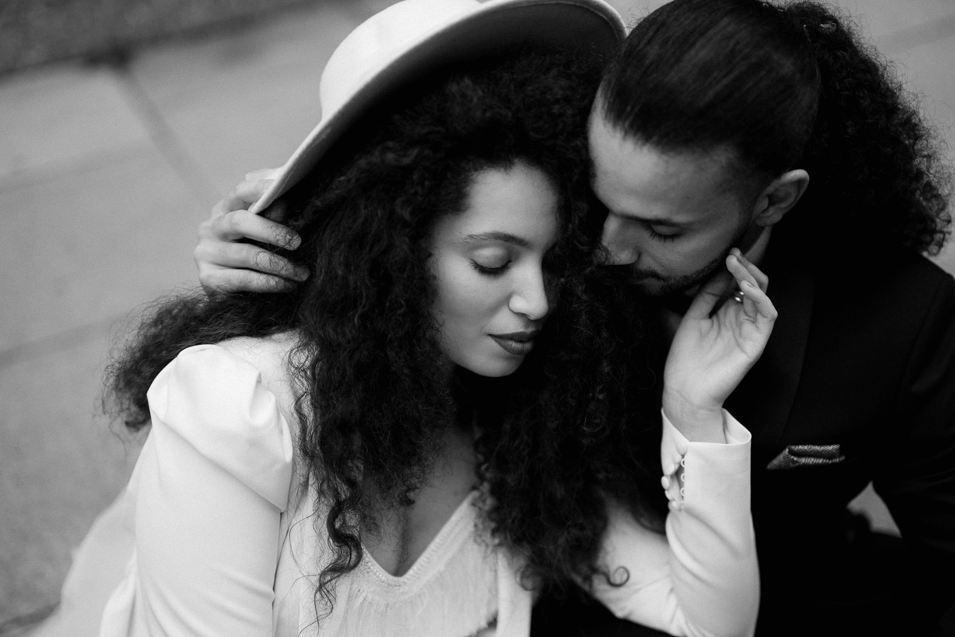 bride and groom sitting on pavement cuddling
