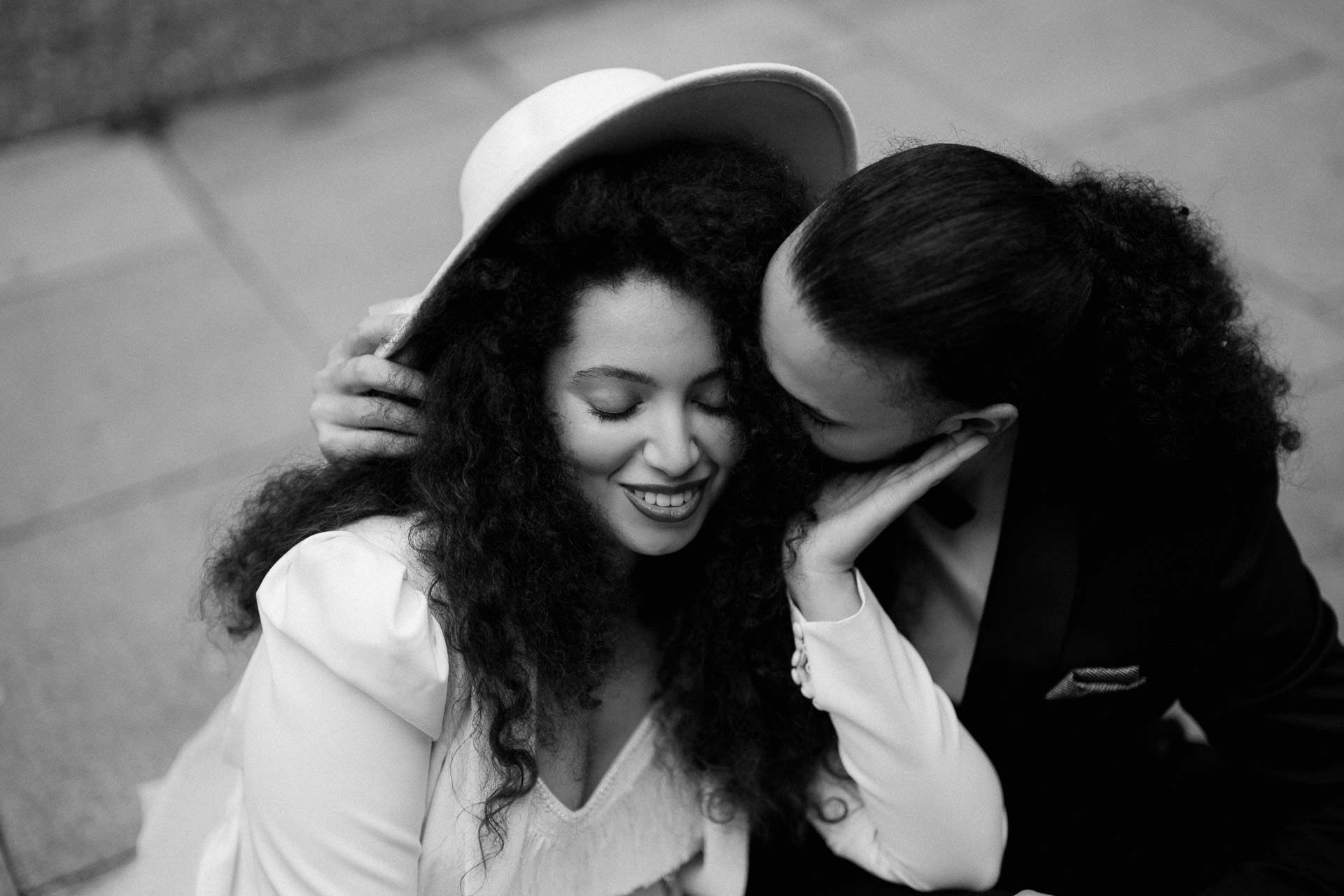 bride and groom sitting on pavement cuddling