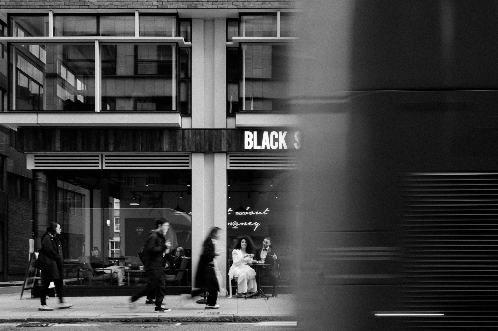 bride and groom at coffee shop drinking coffee with people and cars going past