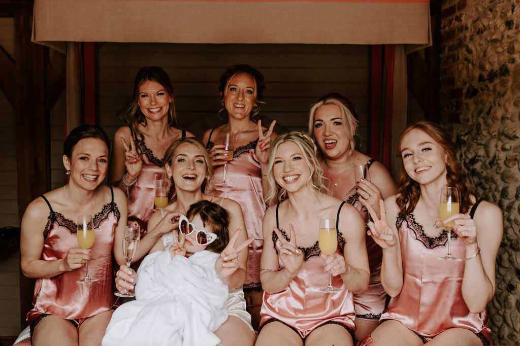 bride in dressing down with bridesmaids on bed at retreat east