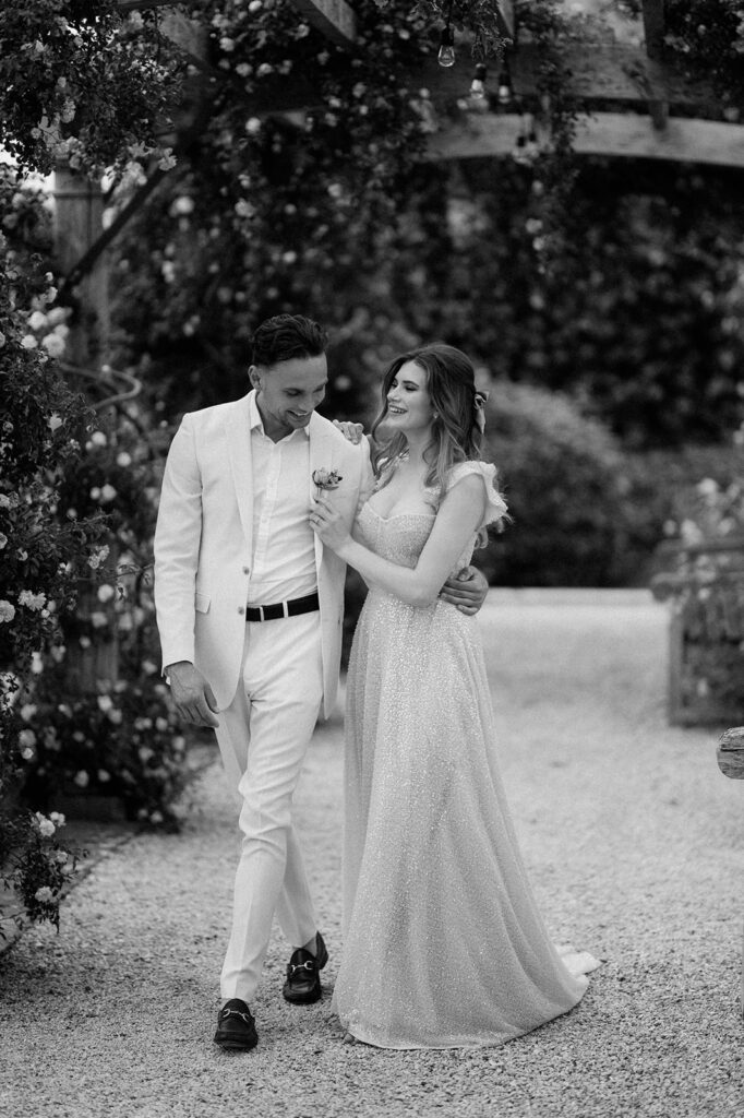 bride and groom walking through rose garden at euridge manor