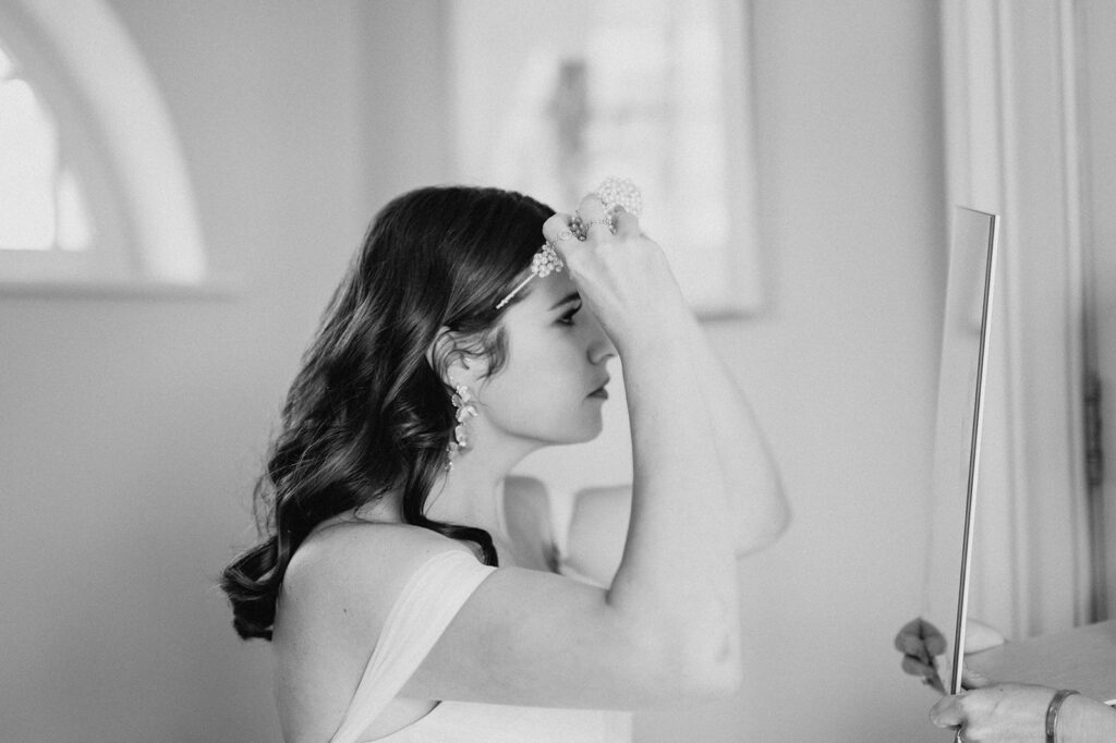 bride putting on headpiece 