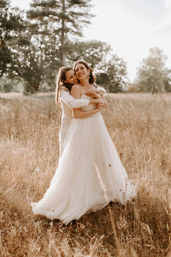 bride hugging bride in wedding dress from behind