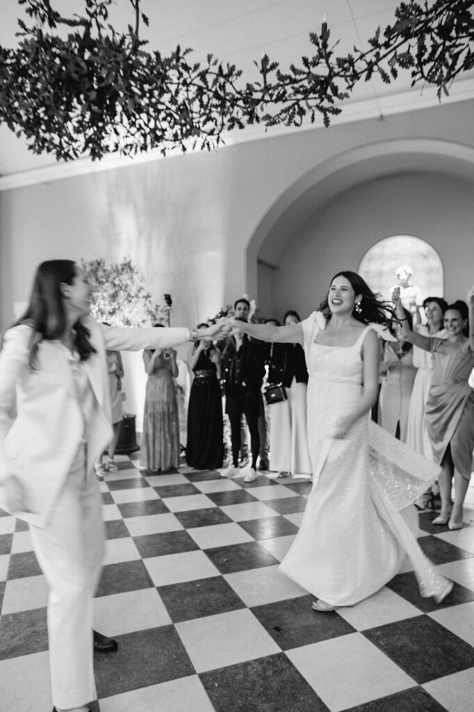 two brides having first dance in orangery at wilderness reserve with guests watching
