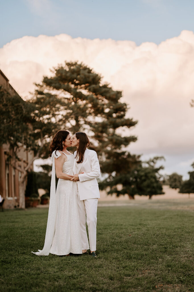 bride in sparkly dress kissing bride in wedding suit