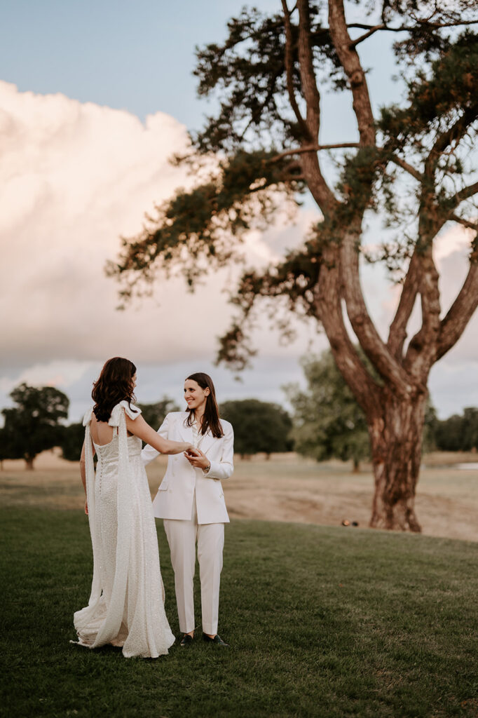 bride in sparkly dress dancing with bride in wedding suit