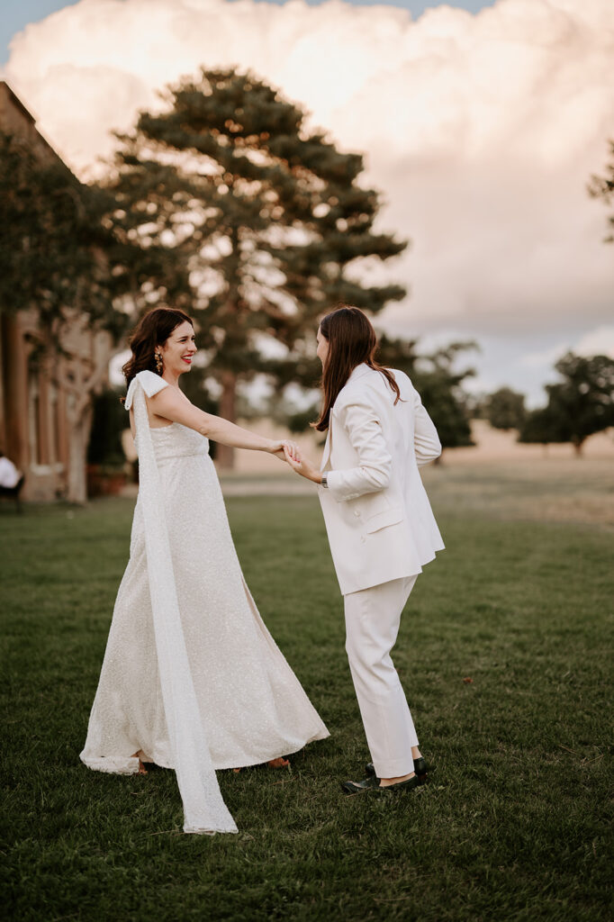 bride in sparkly dress dancing with bride in wedding suit
