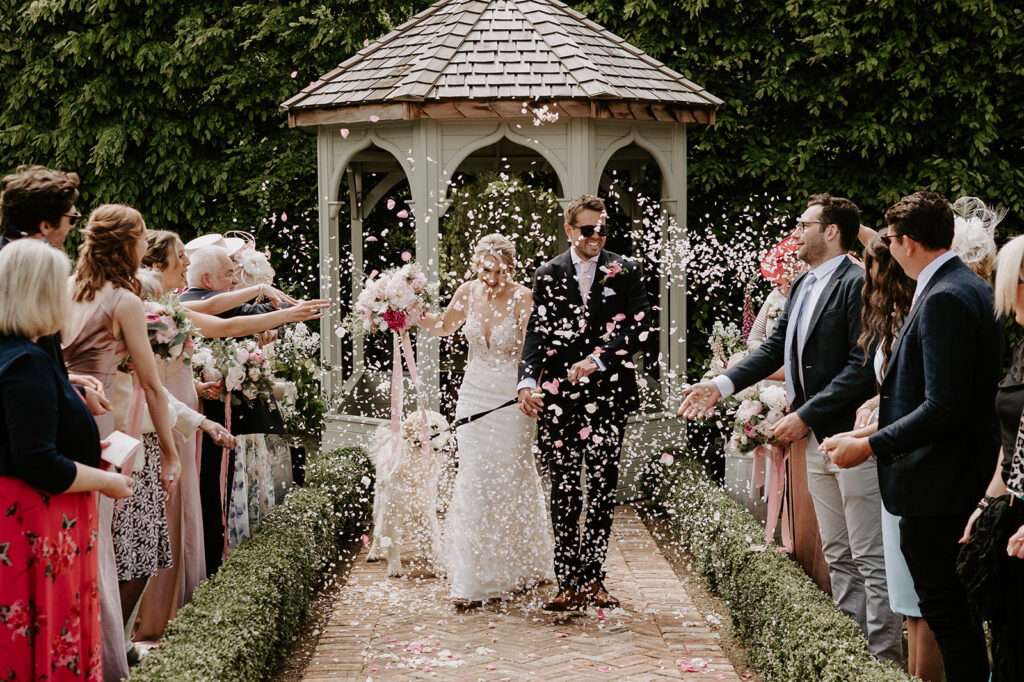 couple walking back down aisle with their dog and confetti being thrown by guests at retreat east