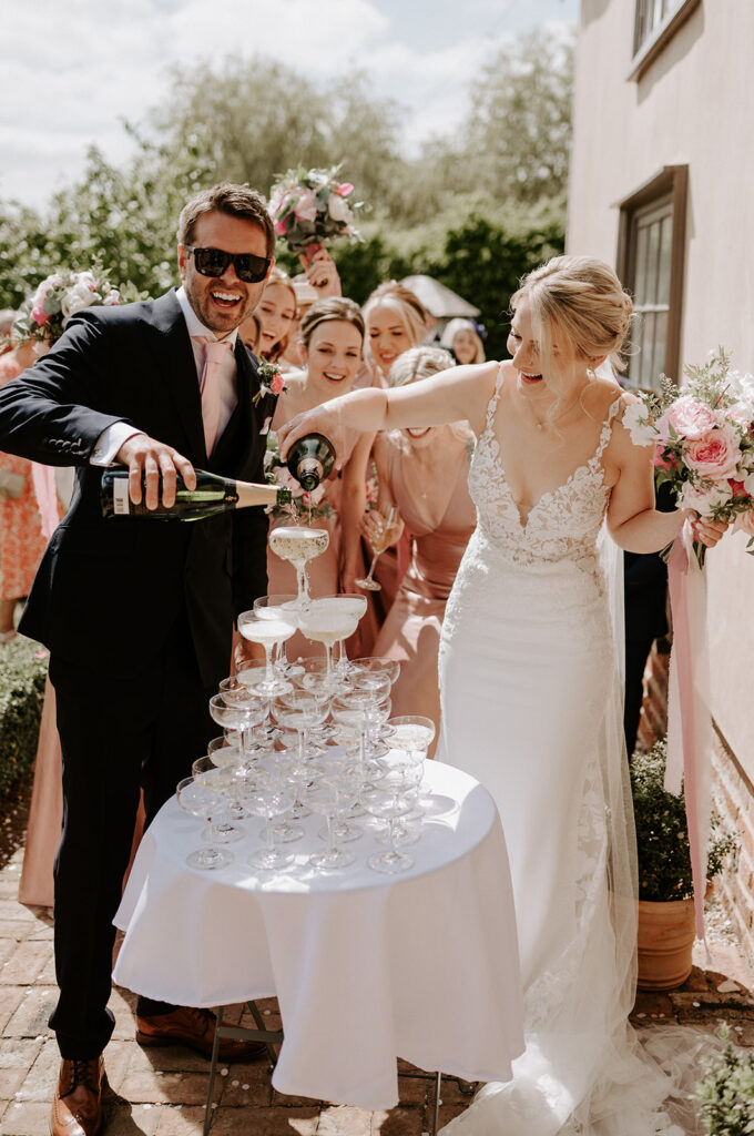 bride and groom pouring champagne into champagne tower at retreat east