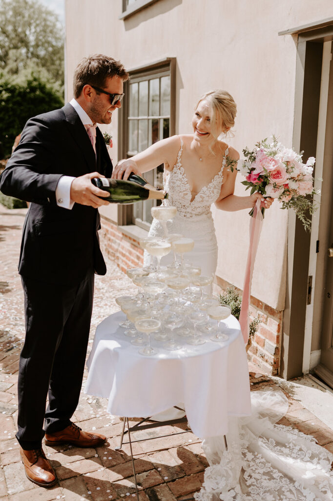 bride and groom pouring champagne into champagne tower at retreat east