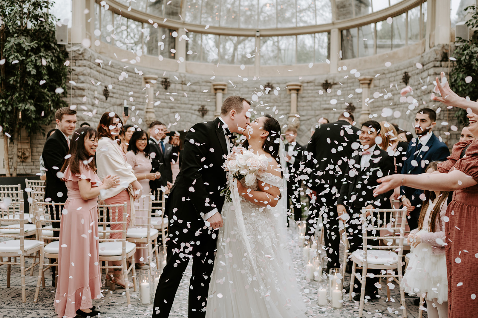 wedding guests throwing confetti over bride and groom