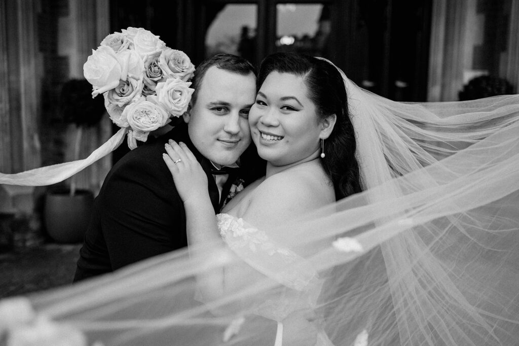 bride and groom with veil floating in wind holding blush pink rose bouquet