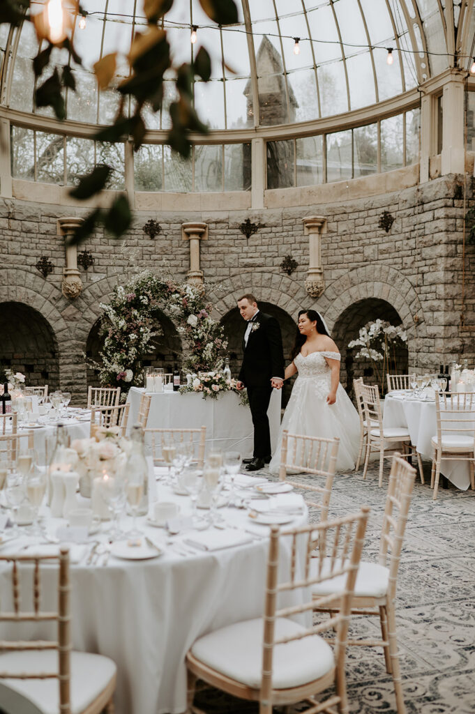 bride and groom walking around wedding breakfast set up in orangery at tortworth court