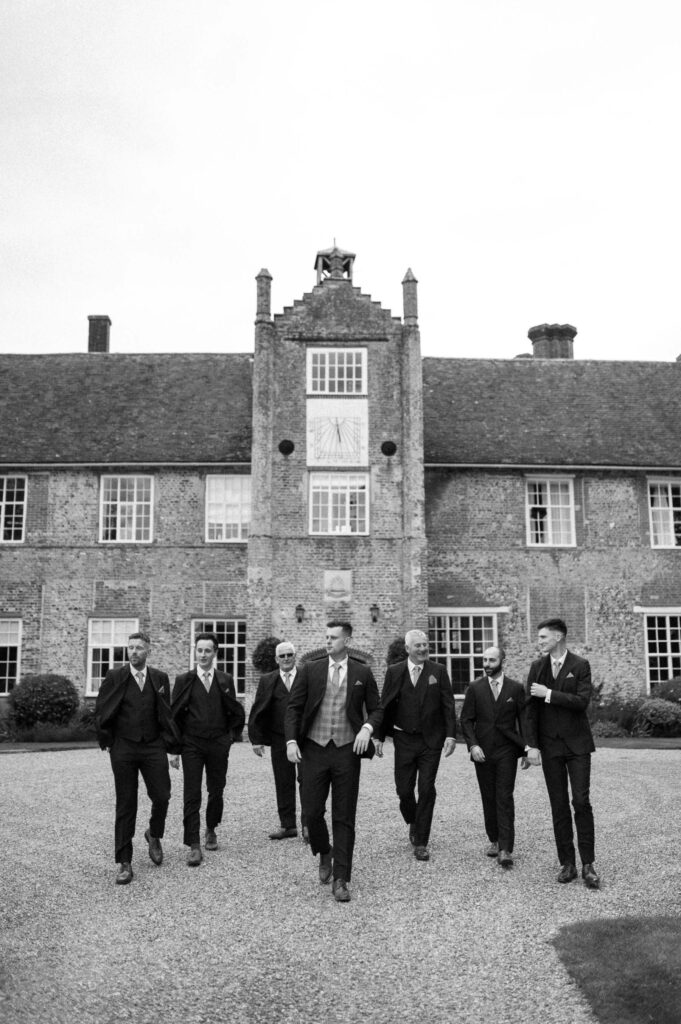 Black and white photo of groomsmen standing together outside Bruisyard Hall
