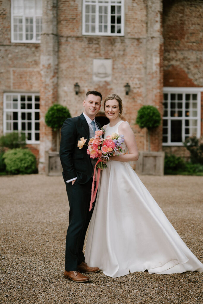 Bride and groom standing together outside the main entrance at Bruisyard Hall