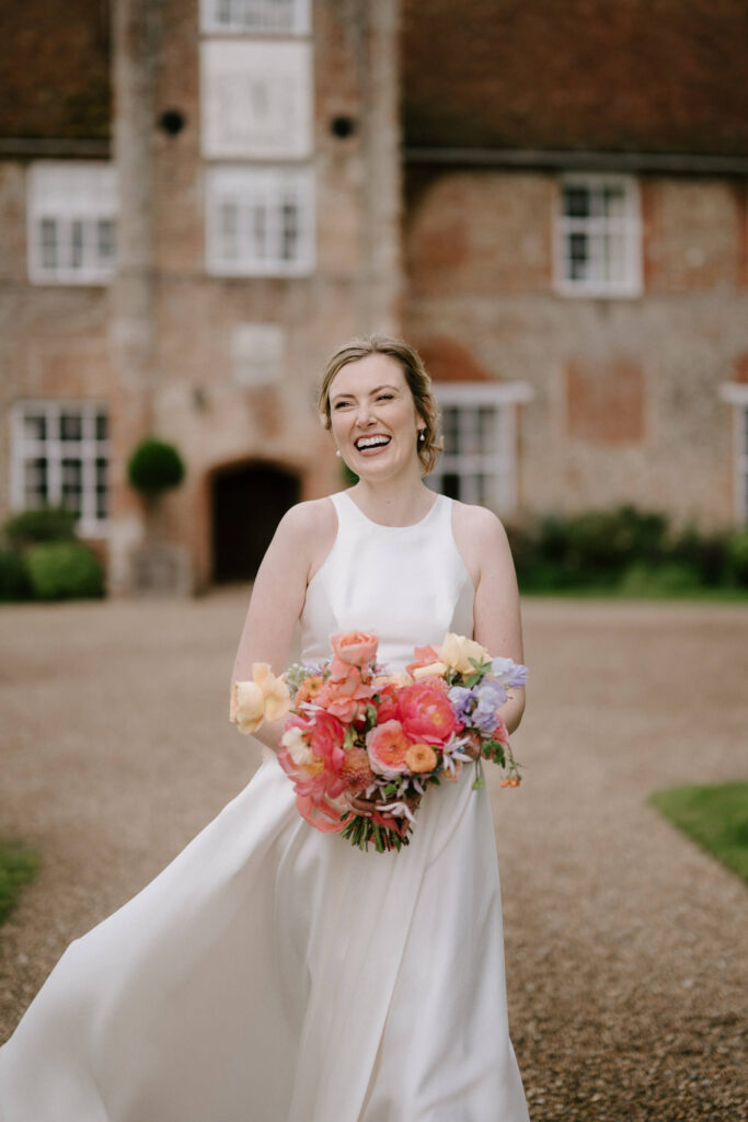 Bride standing and smiling with her bouquet at Bruisyard Hall