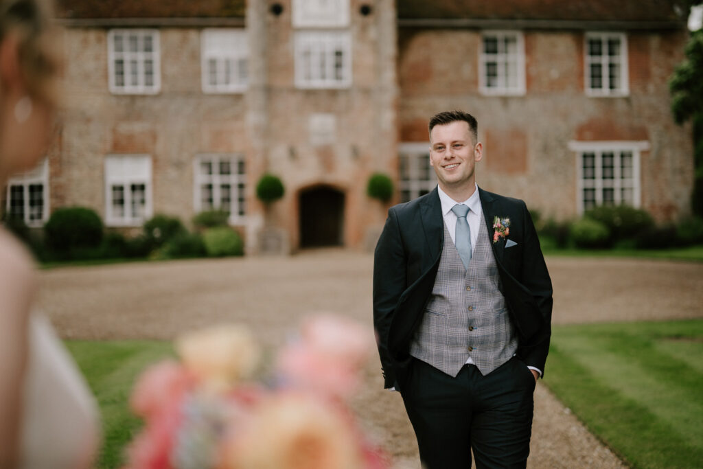 Groom walking towards bride outside Bruisyard Hall