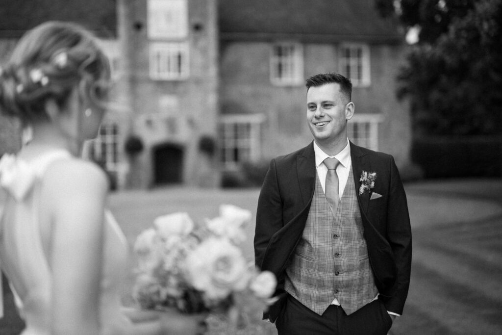 groom smiling at bride outside Bruisyard Hall